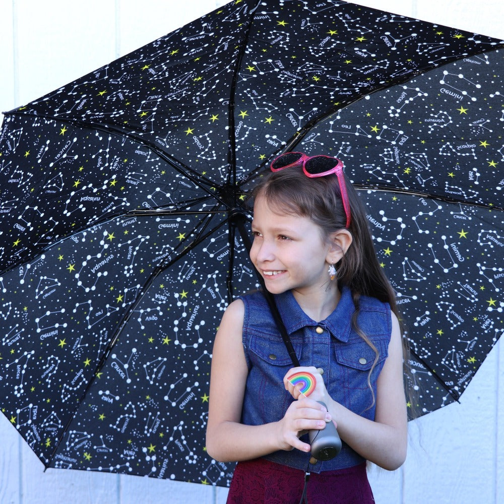 Young kid holding InBrella Reverse Close Folding Umbrella in zodiac black front view 